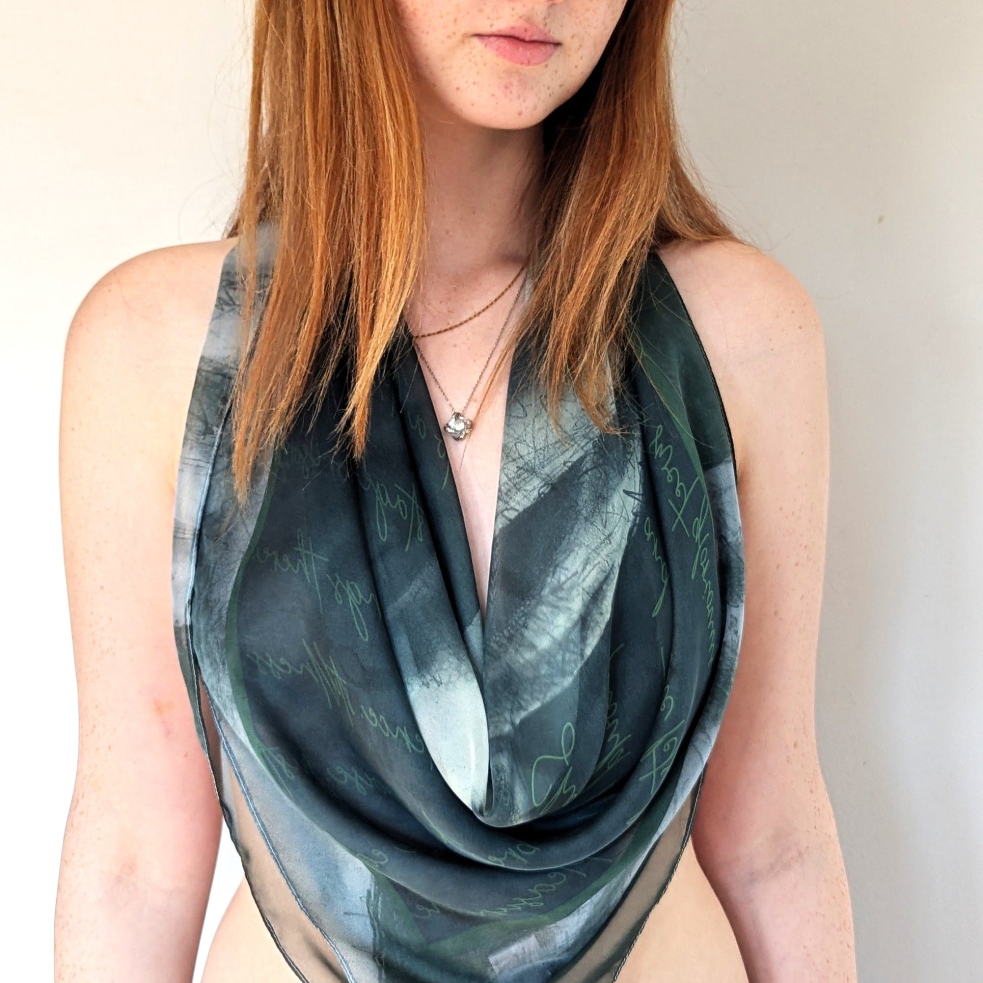 Model wears a Scandalous scarf in green 'Watch Mm' as a draped wrap cowl neck top  - she looks sophisticated and chic