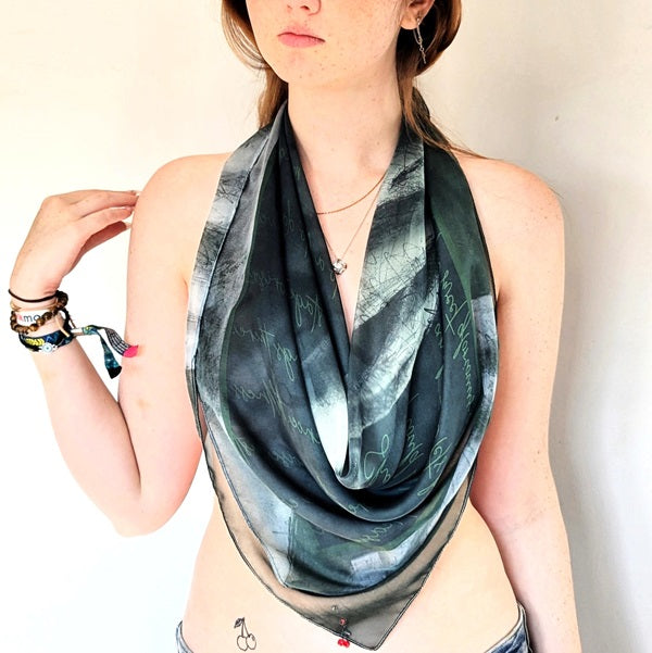 Model wears a Scandalous scarf in green 'Watch Mm' as a draped wrap cowl neck top  - she looks sophisticated and chic